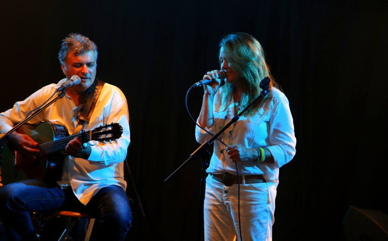 Tal singing on stage beside a guitarist